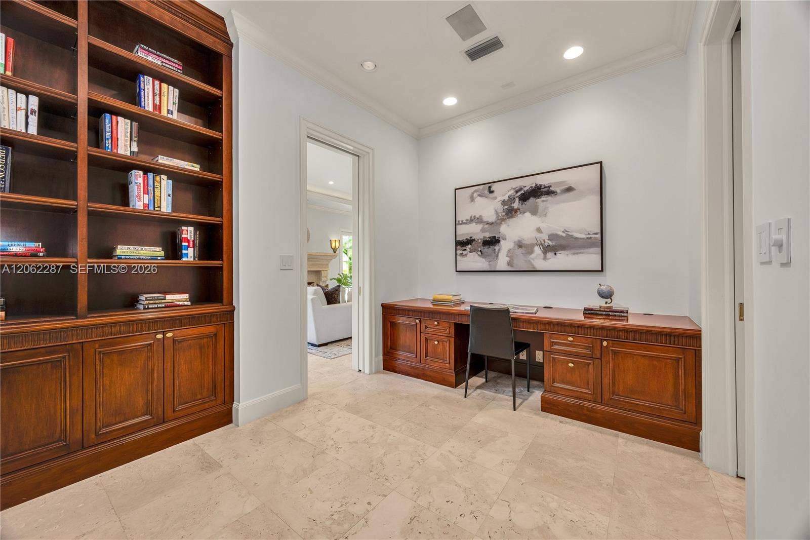 Custom wood-finish floor-to-ceiling cabinetry, integrated wooden built-in desk, stone tile flooring, and recessed ceiling lighting
