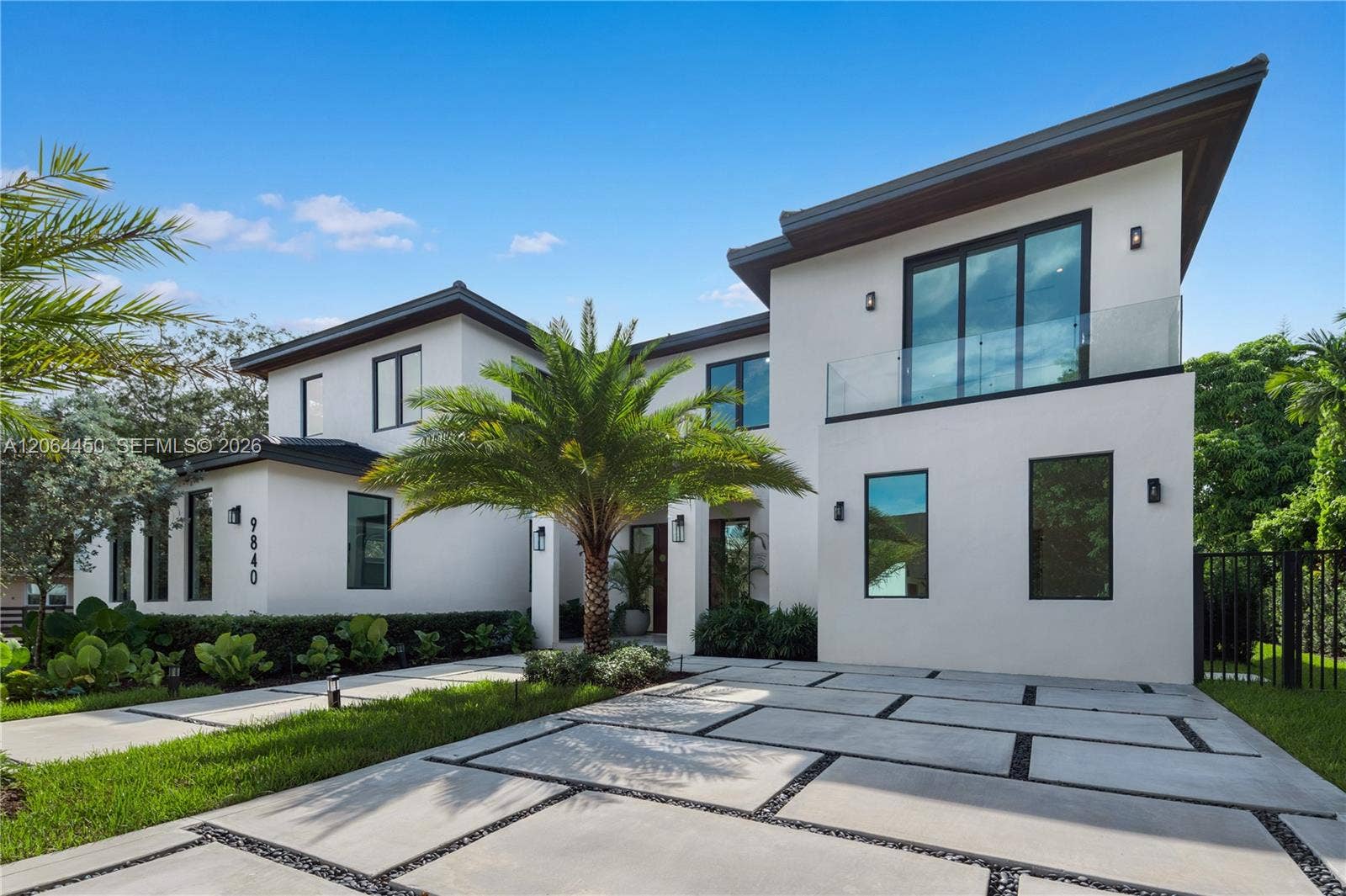 Contemporary facade with clean white lines, expansive glass, and a wide paver motor court
