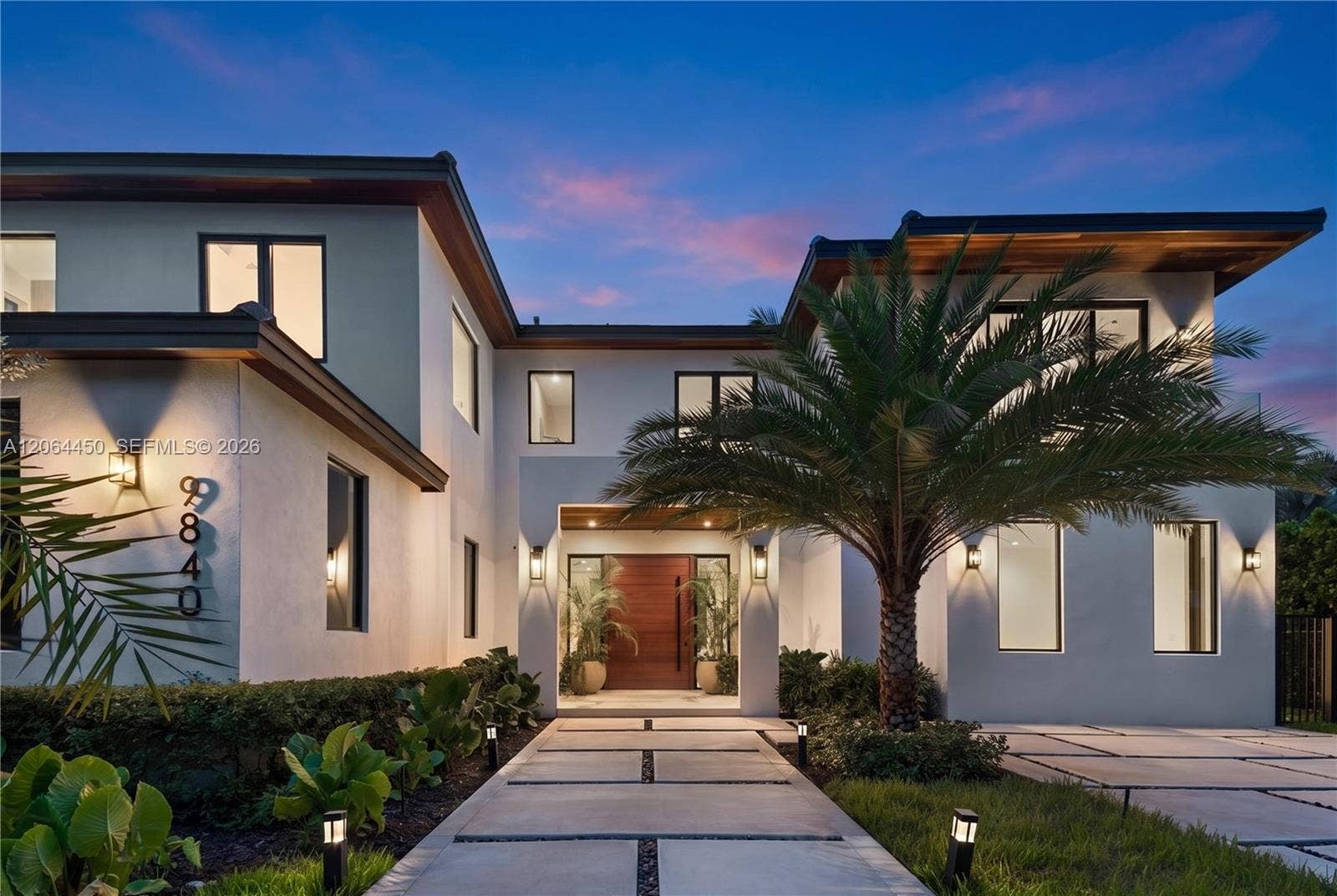 Front elevation at dusk, warmly lit against the evening sky