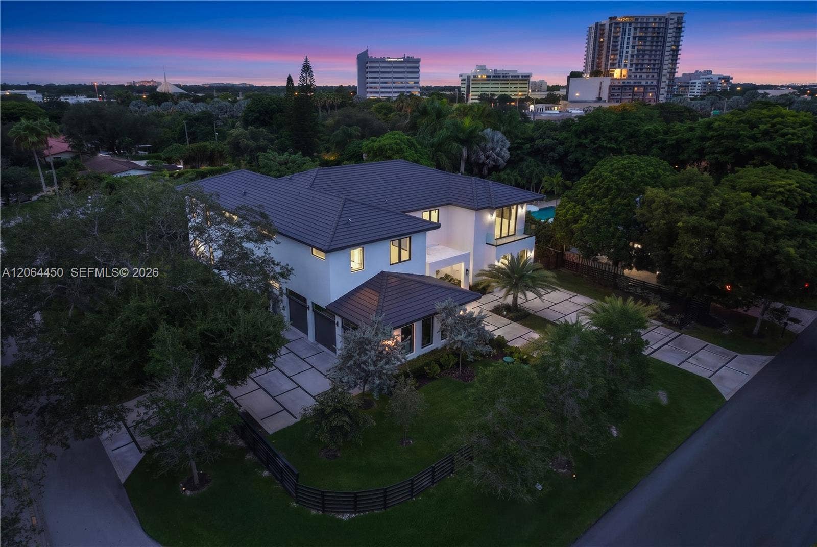 Twilight aerial of the property with the city lights on the horizon
