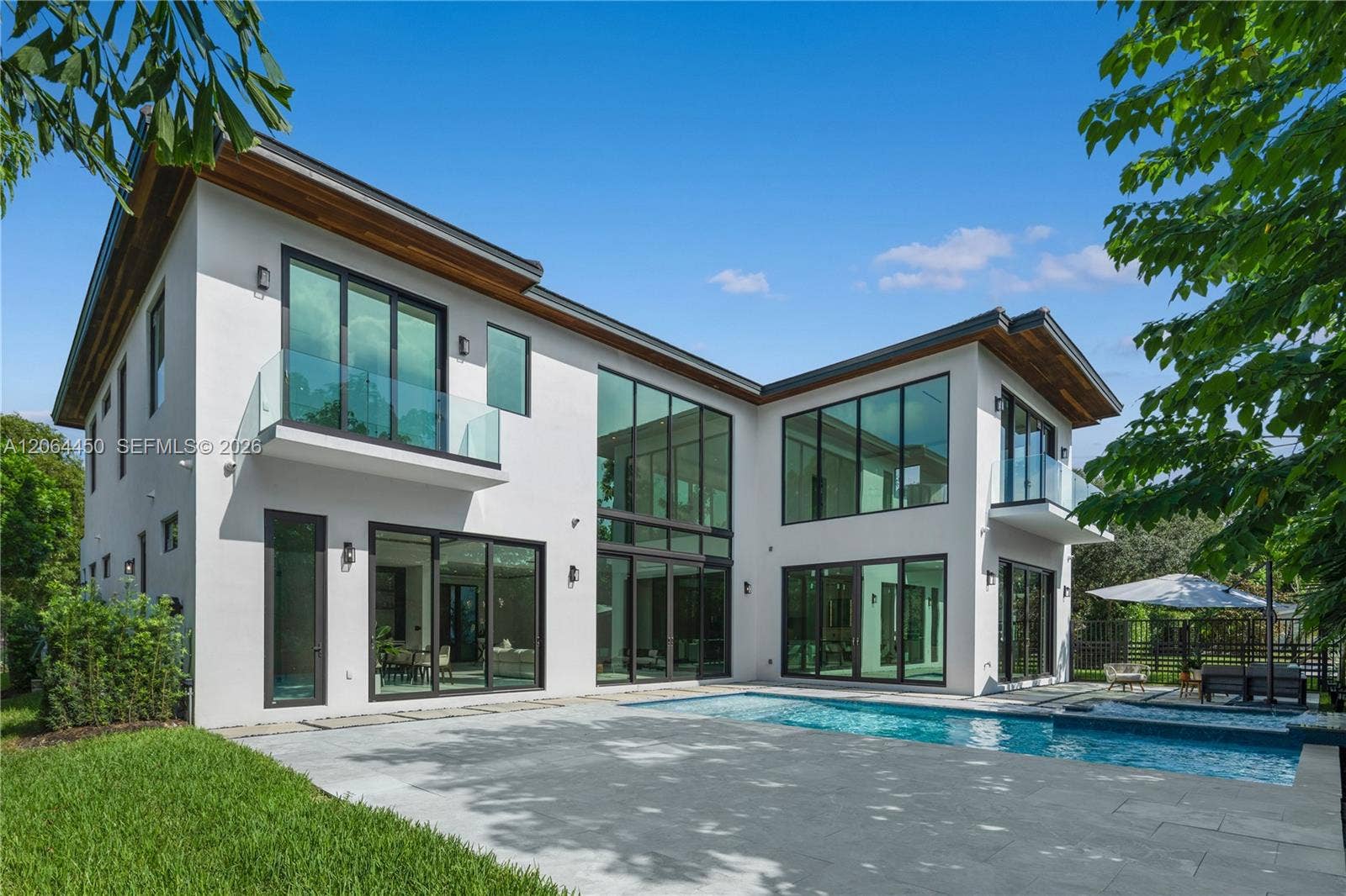 Backyard view of the home, pool deck, and landscaped lawn