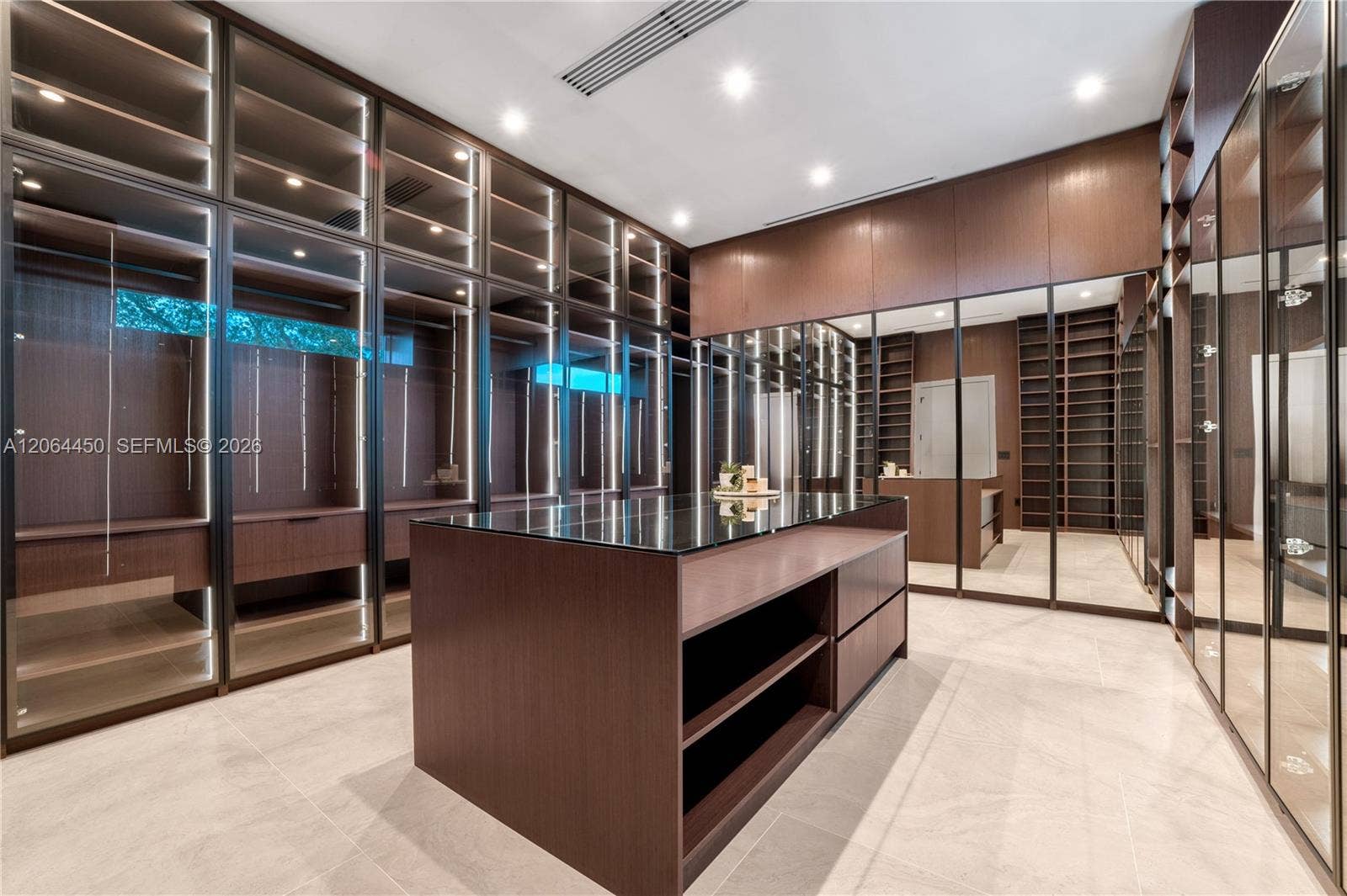 Boutique style closet with glass front cabinetry, lighting, and a center island