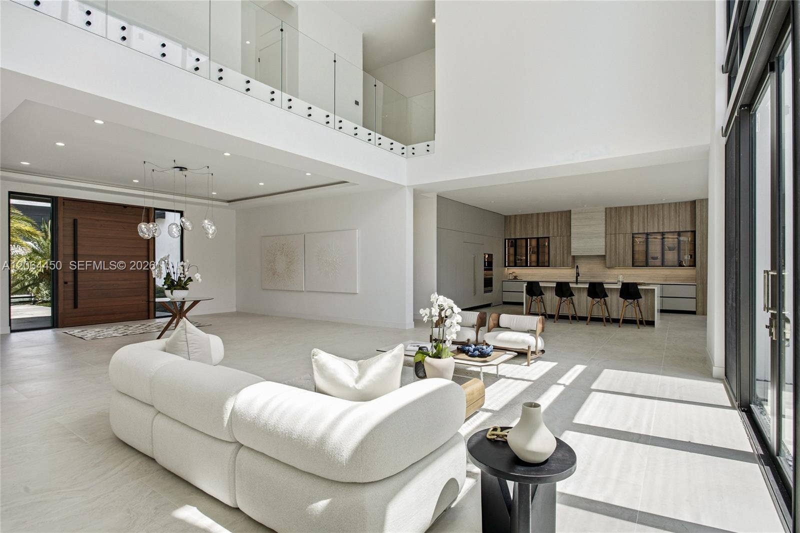 Great room facing the kitchen and bar seating under soaring ceilings