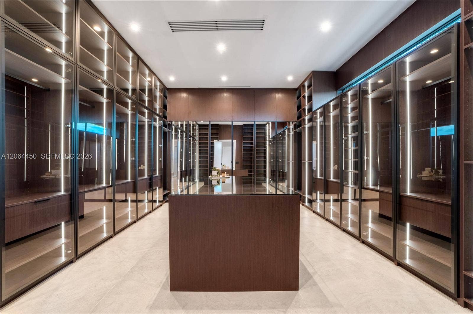 Dressing room with illuminated display cabinetry and a center storage island