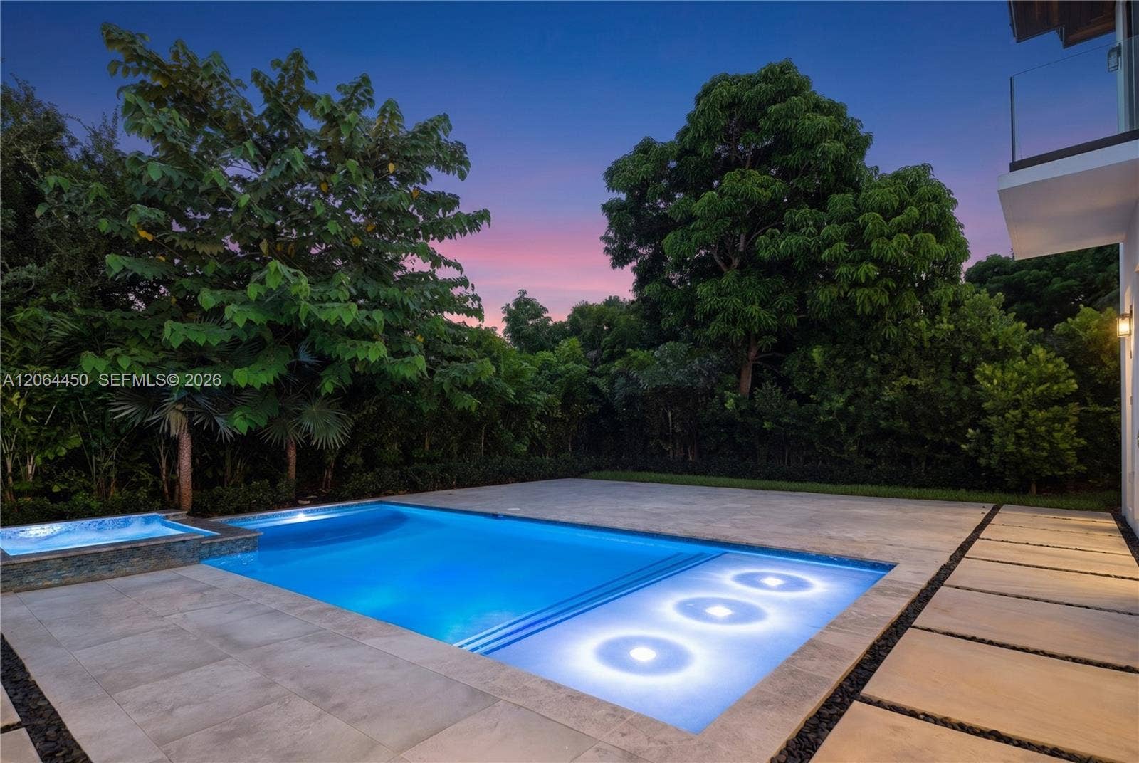 Pool illuminated at night with privacy from lush surrounding landscaping