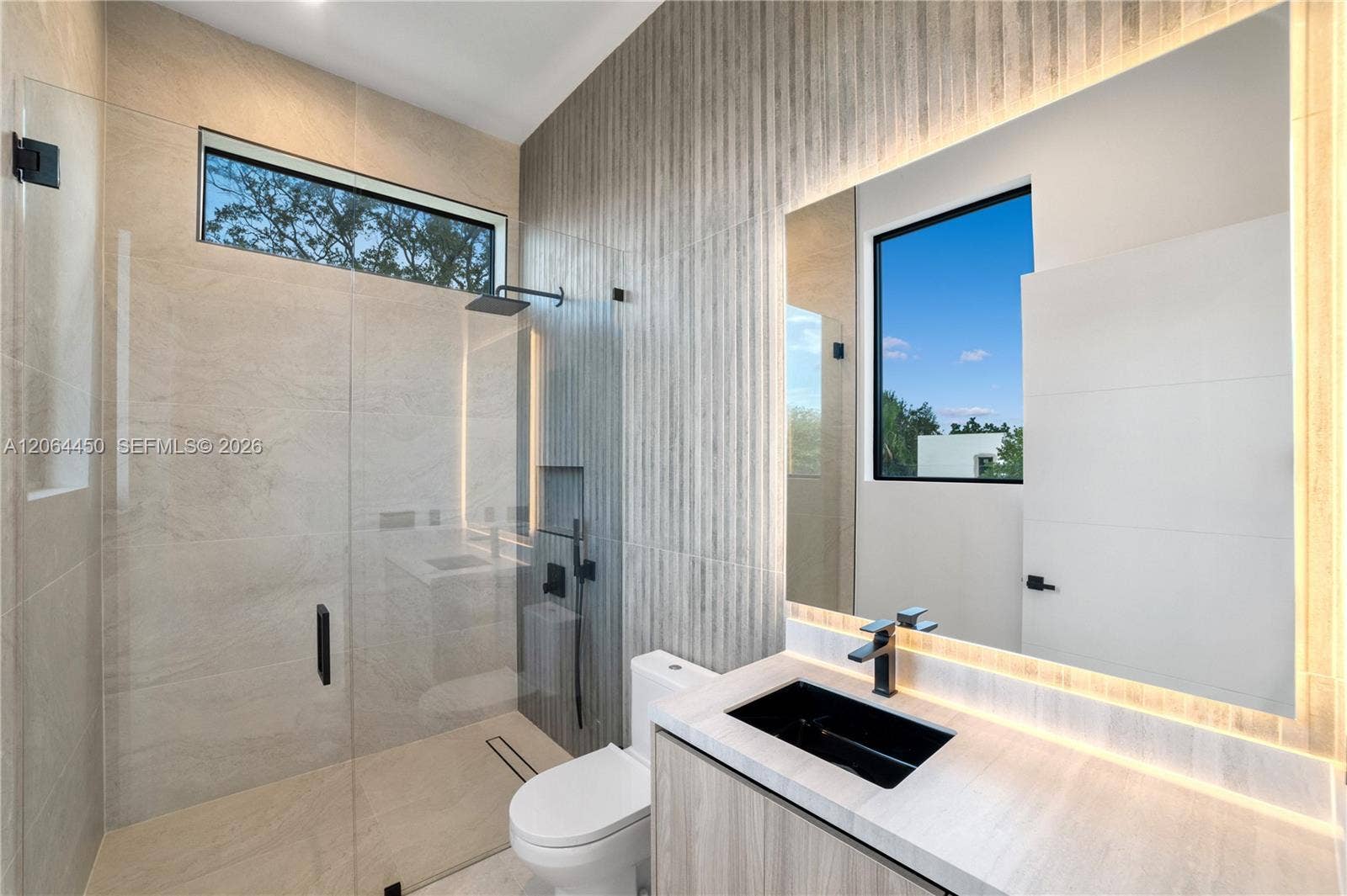 Spa inspired bath with backlit mirror, floating vanity, and glass enclosed shower