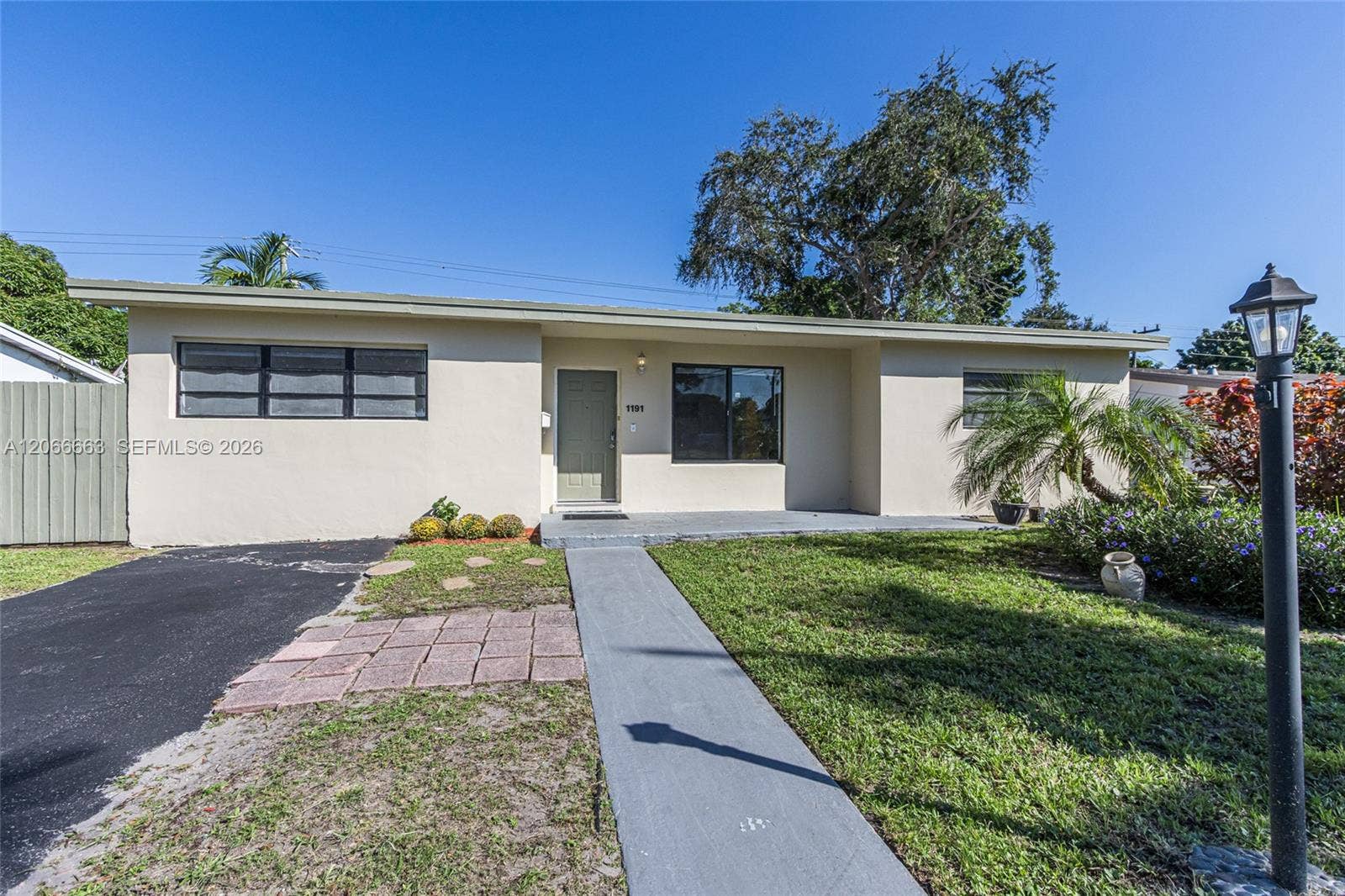 1191 NE 175th Street, North Miami Beach, FL 33162 Single-story exterior featuring a low-pitched roof, smooth stucco finish, asphalt driveway, and a concrete walkway