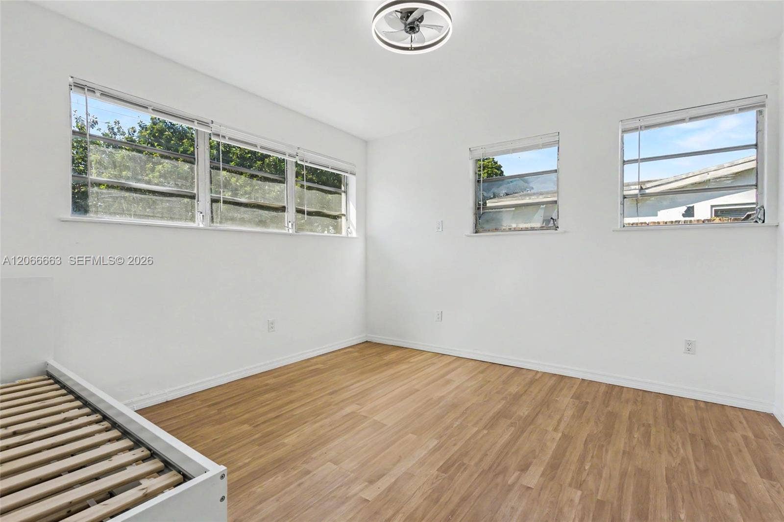 1191 NE 175th Street, North Miami Beach, FL 33162 Bright interior featuring wood-finish flooring, multi-pane casement windows, and a modern circular ceiling fan with integrated lighting