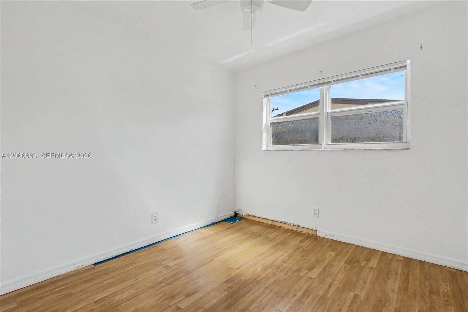 1191 NE 175th Street, North Miami Beach, FL 33162 Interior room featuring wood-finish flooring, white walls, a horizontal sliding window, and a ceiling fan