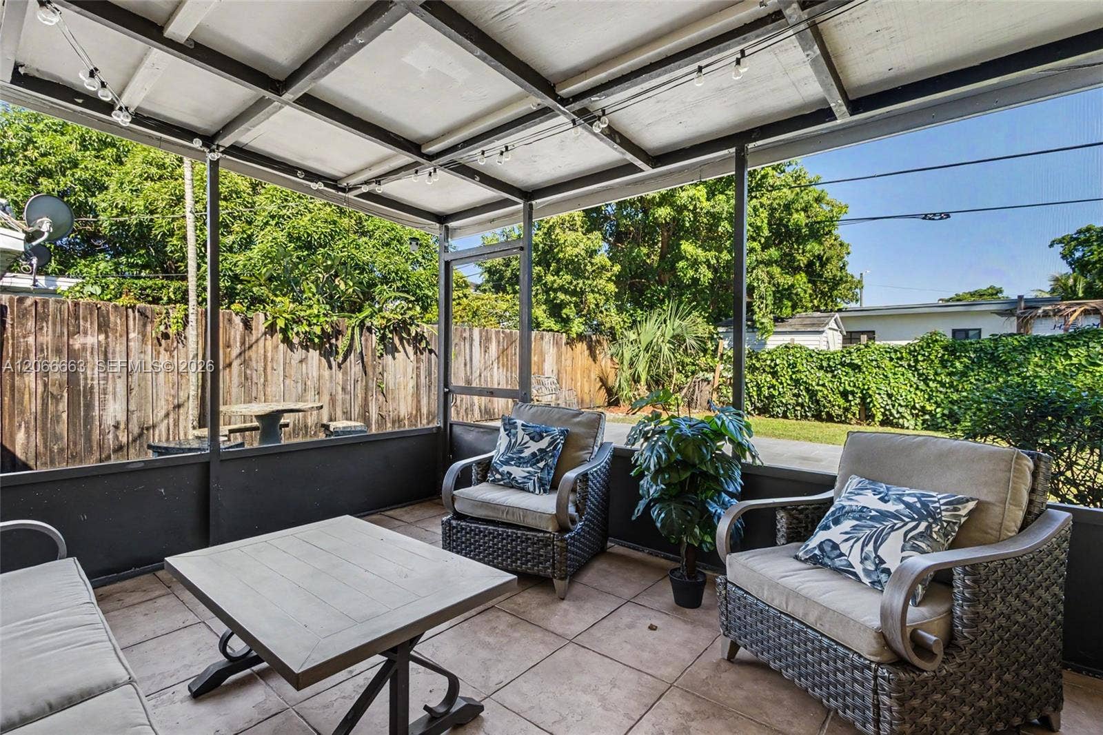 1191 NE 175th Street, North Miami Beach, FL 33162 Screened-in porch featuring a metal frame, tile flooring, and wood-panel perimeter fencing