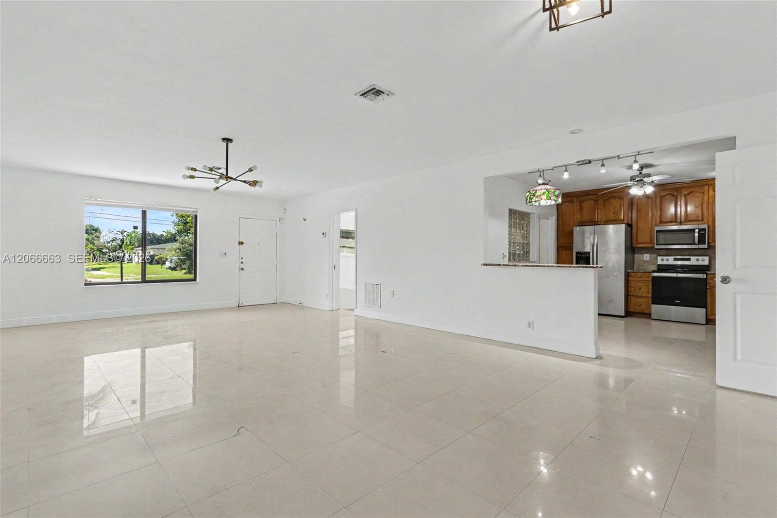1191 NE 175th Street, North Miami Beach, FL 33162 Open-concept interior featuring large-format tile flooring, recessed lighting, a breakfast bar, and kitchen cabinetry with stainless steel appliances