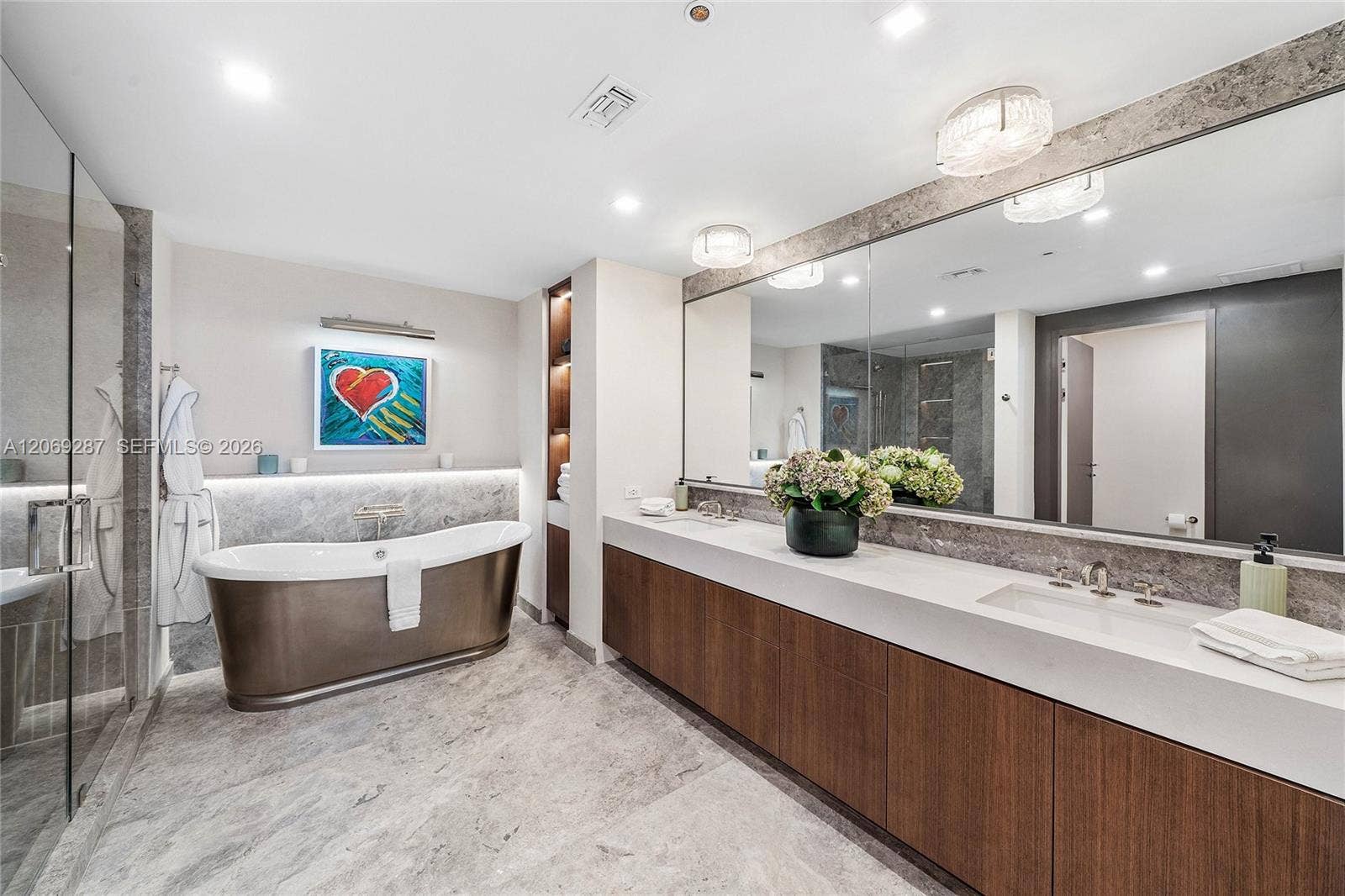 435 Bayshore Drive, #703, Fort Lauderdale, FL 33304 An en-suite bathroom featuring elegant finishes, dual vanities, a soaking tub and an oversized glass-enclosed shower.