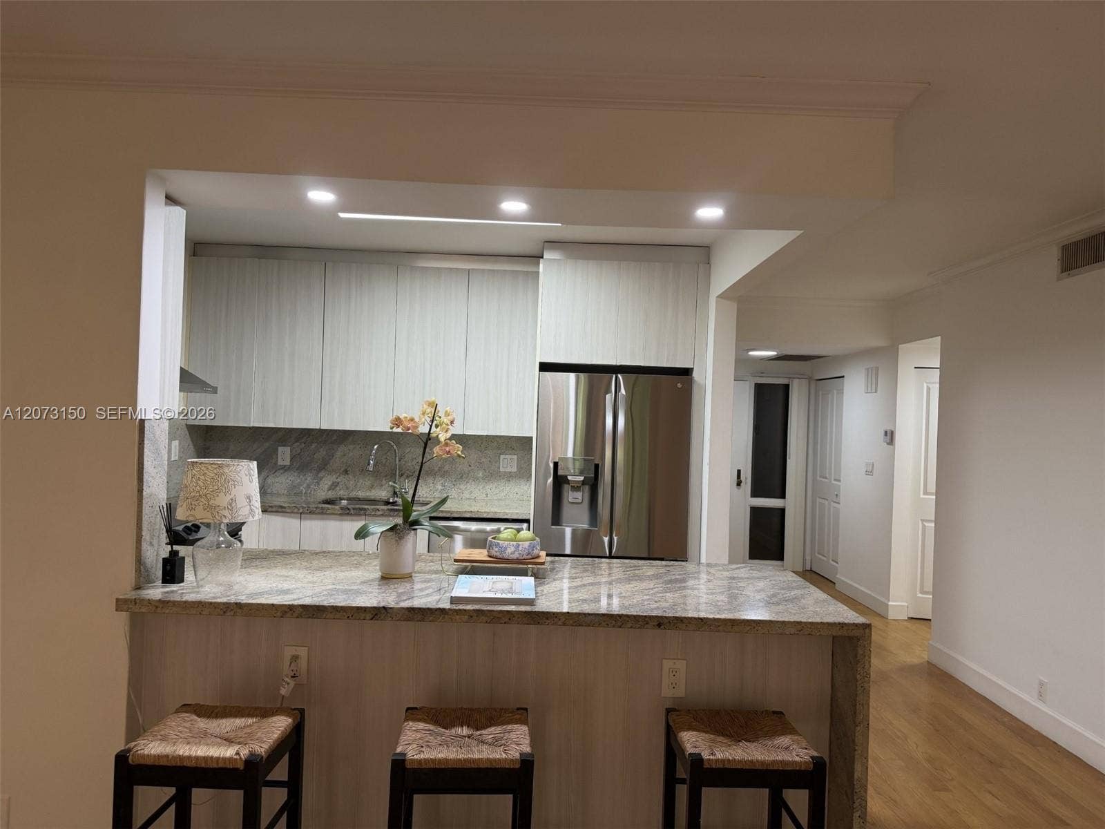 141 Crandon Boulevard, #243, Key Biscayne, Key Biscayne, FL 33149 Kitchen featuring a stone-surface breakfast bar, light-tone cabinetry, recessed ceiling lighting, and stainless steel appliances