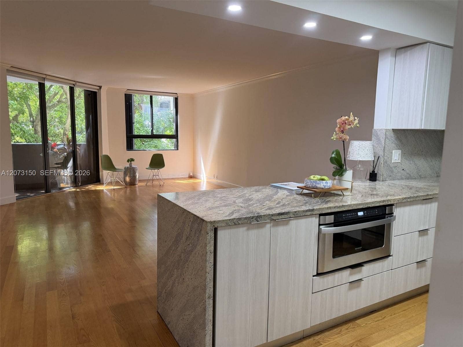 141 Crandon Boulevard, #243, Key Biscayne, Key Biscayne, FL 33149 Kitchen featuring an island with stone-finish countertops and built-in microwave, light-toned cabinetry, recessed lighting, and wood-finish flooring throughout