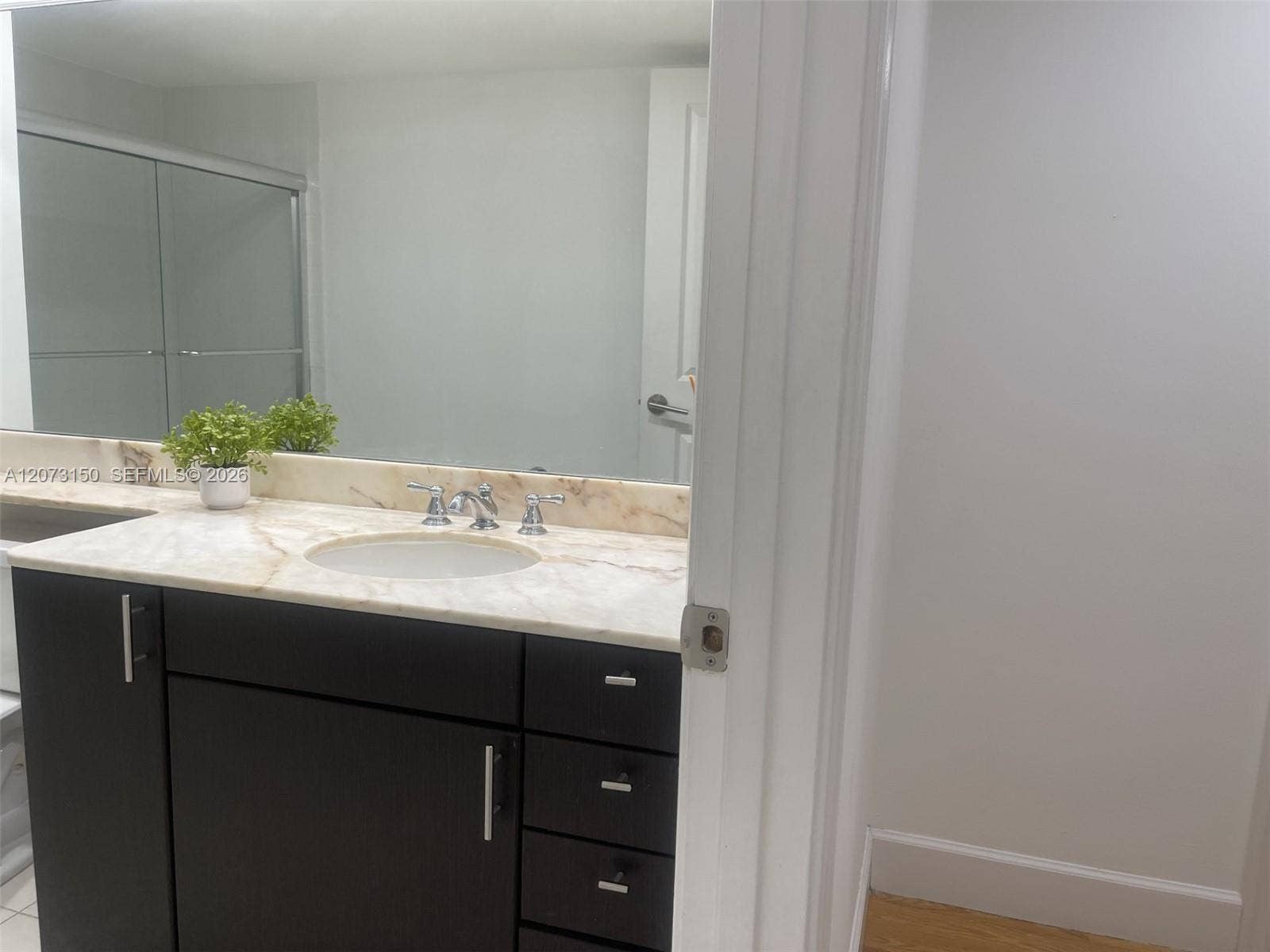 141 Crandon Boulevard, #243, Key Biscayne, Key Biscayne, FL 33149 Dark cabinetry with silver-tone hardware, stone-surface countertop, integrated basin, widespread chrome faucet, and expansive wall-mounted mirror
