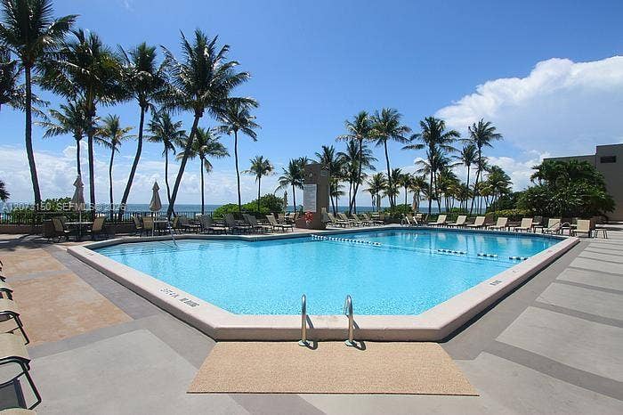 141 Crandon Boulevard, #243, Key Biscayne, Key Biscayne, FL 33149 In-ground swimming pool featuring a concrete deck, metal handrails, and mature palm trees