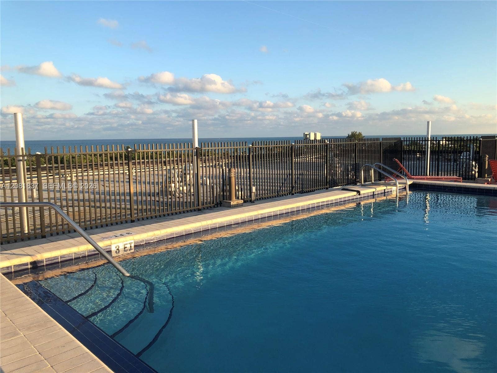 8233 Harding Avenue, #707, Miami Beach, Miami Beach, FL 33141 In-ground swimming pool featuring a tiled waterline, metal safety fencing, integrated entry steps, and stainless steel handrails