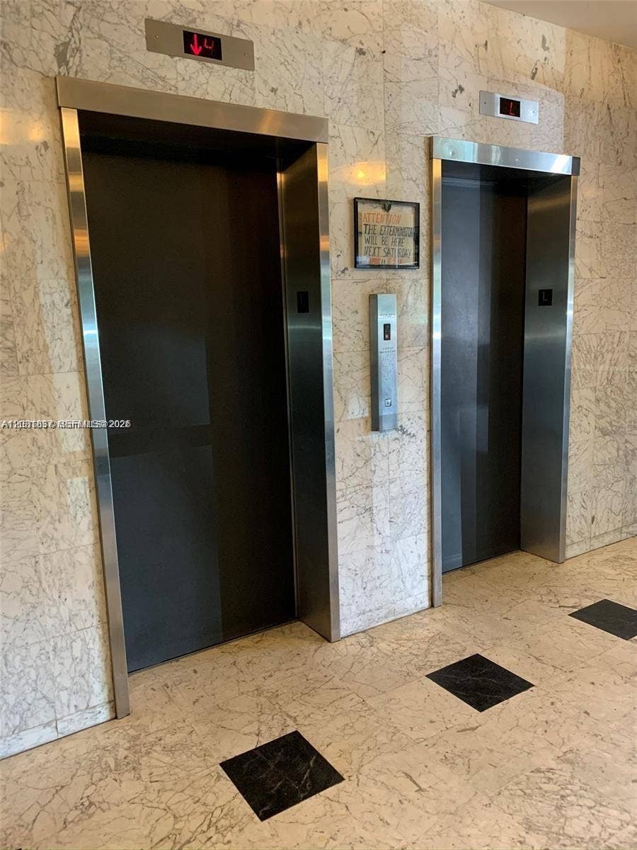 8233 Harding Avenue, #707, Miami Beach, Miami Beach, FL 33141 Dual stainless steel elevator doors framed by polished stone wall cladding and stone tile flooring with decorative square inlays
