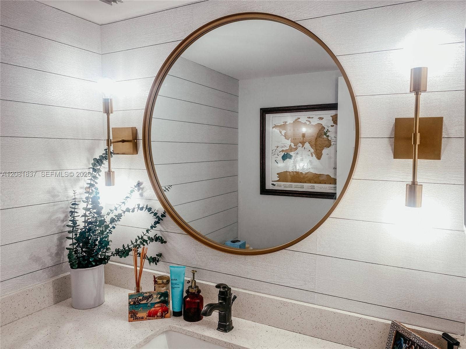 8233 Harding Avenue, #707, Miami Beach, Miami Beach, FL 33141 Round mirror with a metallic frame, horizontal plank wall cladding, integrated stone-surface countertop, and dual vertical wall-mounted fixtures with metallic finishes