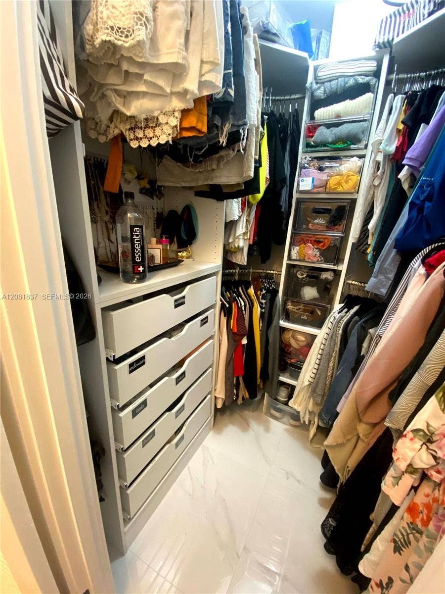8233 Harding Avenue, #707, Miami Beach, Miami Beach, FL 33141 Walk-in closet featuring white built-in cabinetry, custom drawer stack, integrated shelving, and stone-finish flooring