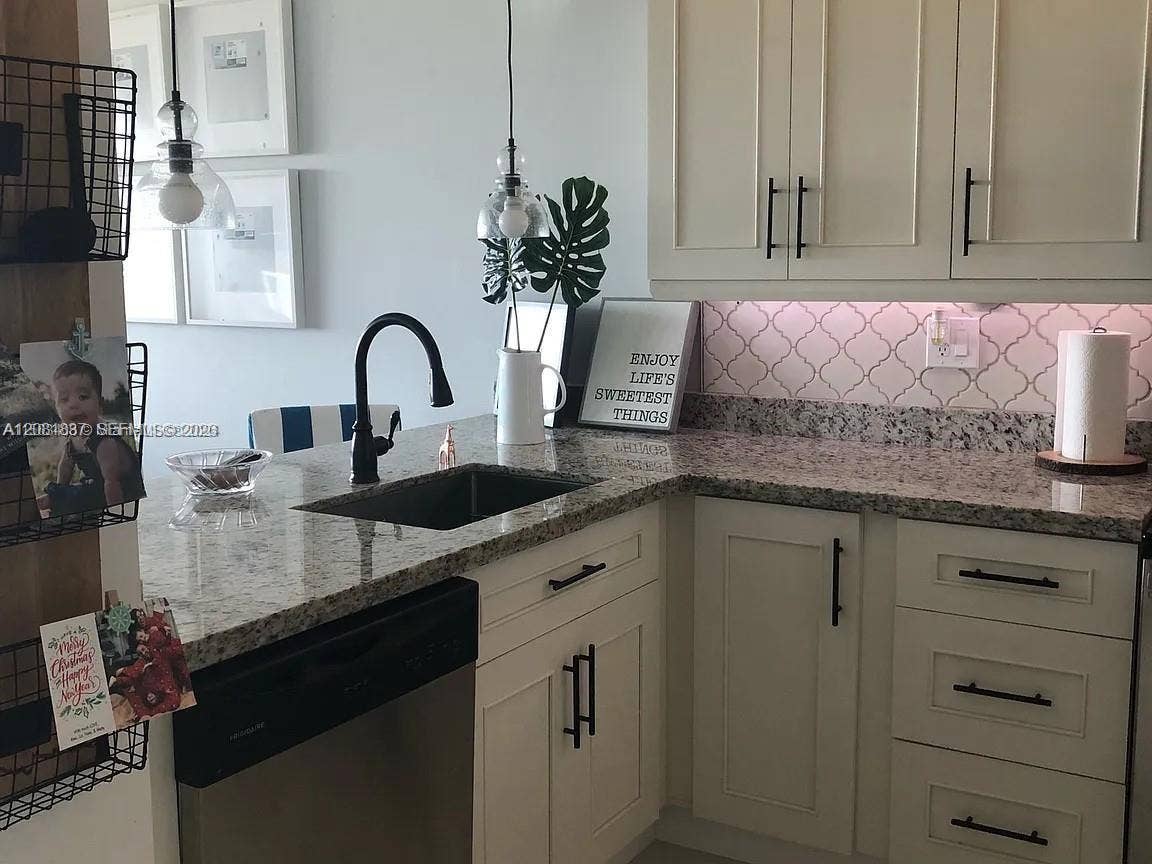 8233 Harding Avenue, #707, Miami Beach, Miami Beach, FL 33141 Kitchen featuring light-toned shaker cabinetry, stone-finish countertops, matte black hardware, an undermount sink with a gooseneck faucet, and patterned tile backsplash