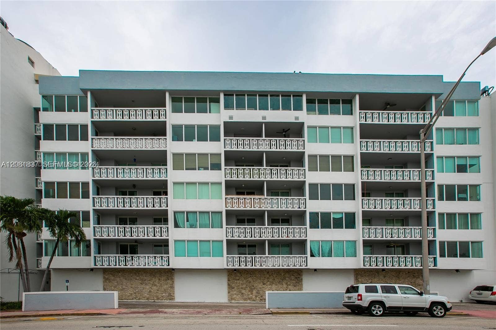 8233 Harding Avenue, #707, Miami Beach, Miami Beach, FL 33141 Multi-story residential building exterior featuring a stone-clad ground level, repetitive rhythmic balconies with patterned railings, and floor-to-ceiling glass fenestration