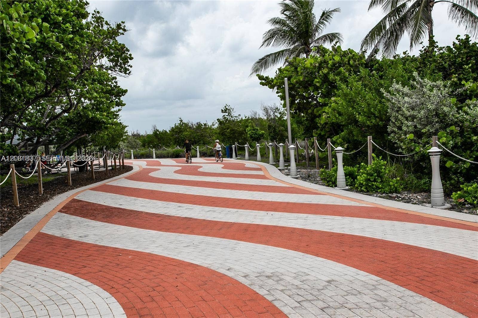 8233 Harding Avenue, #707, Miami Beach, Miami Beach, FL 33141 Winding paved walkway featuring a decorative two-tone brick pattern, bordered by integrated bollard lighting, rope-style railings, and native tropical landscaping