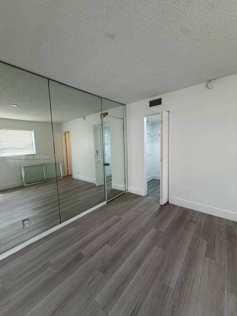 8001 Fairview Drive, #101, Tamarac, Tamarac, FL 33321 Wood-finish flooring, full-wall mirrored paneling, and closet with louvered door