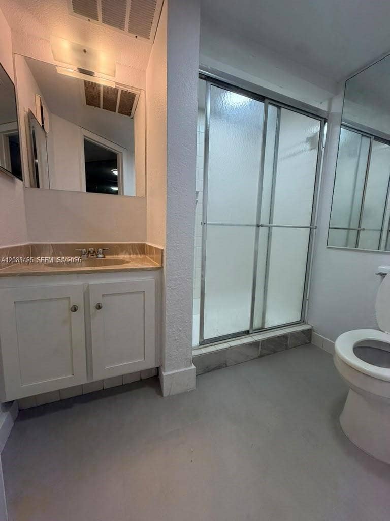 8001 Fairview Drive, #101, Tamarac, Tamarac, FL 33321 Bathroom featuring a vanity with white cabinetry, a neutral countertop with an integrated basin, a walk-in shower with sliding glass doors, and wall-mounted mirrors
