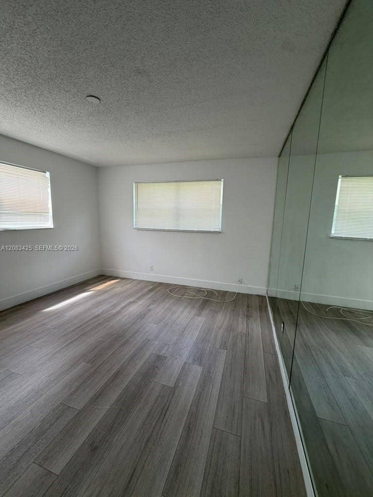 8001 Fairview Drive, #101, Tamarac, Tamarac, FL 33321 Neutral-toned interior featuring wood-finish flooring, full-height mirrored closet doors, and multiple windows