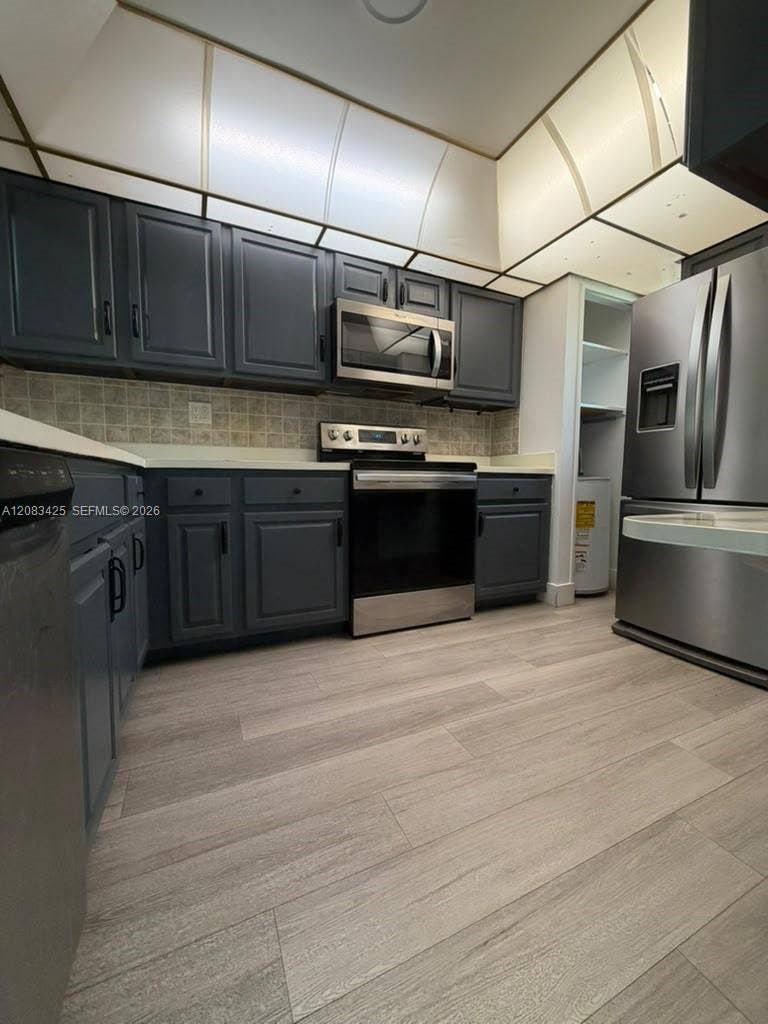 8001 Fairview Drive, #101, Tamarac, Tamarac, FL 33321 Kitchen featuring dark-toned cabinetry, stainless steel appliances, wood-finish flooring, and a coffered ceiling with inset lighting
