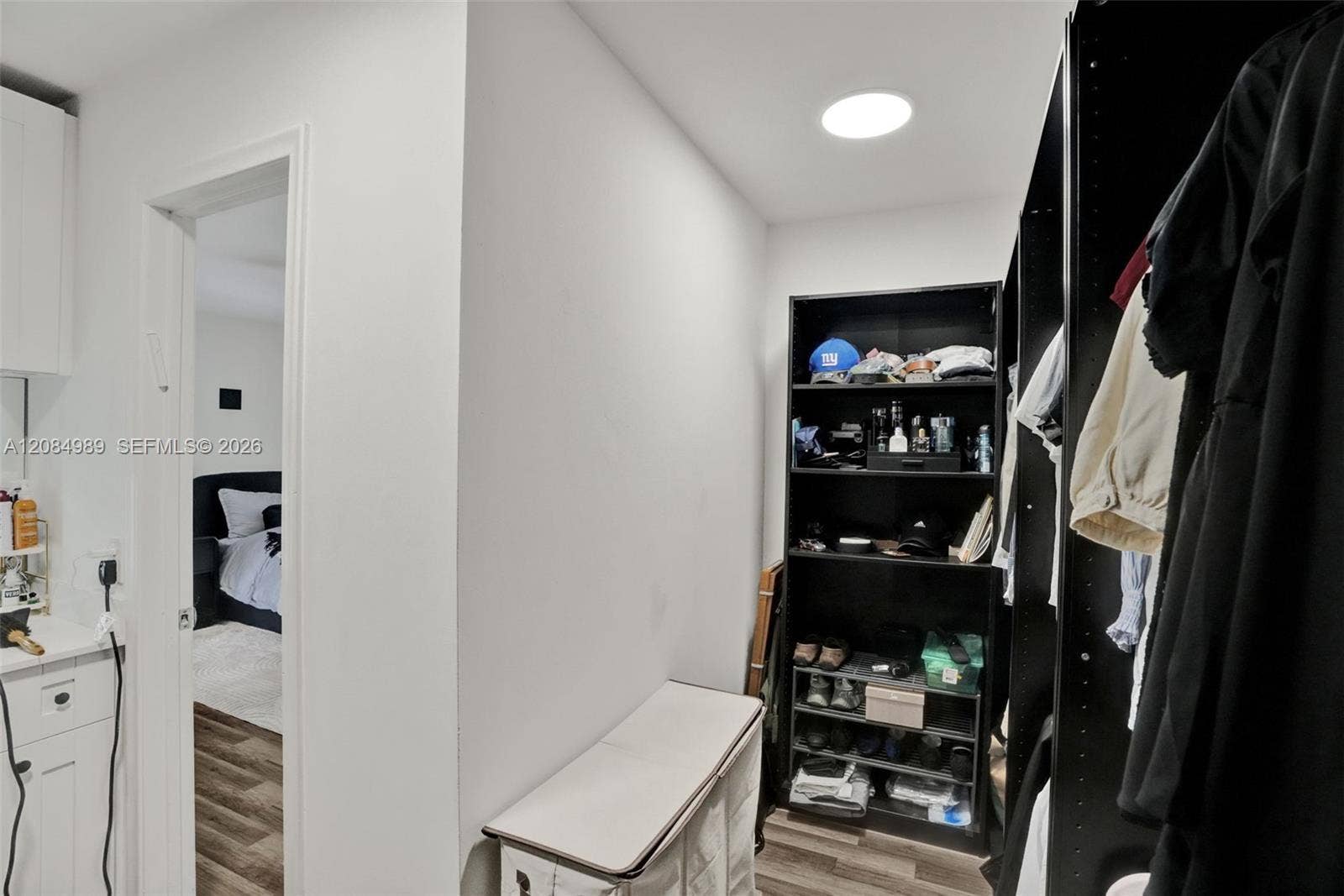 Walk-in storage space featuring wood-finish flooring, recessed ceiling lighting, and built-in vertical shelving units