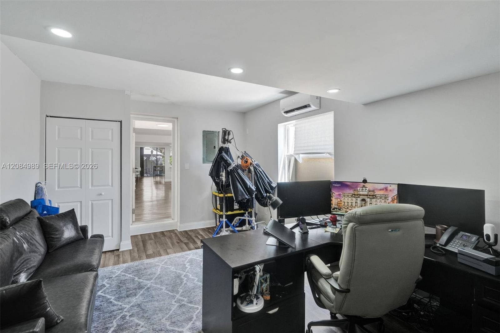 Wood-finish flooring, recessed lighting, wall-mounted climate control unit, and a six-panel closet door