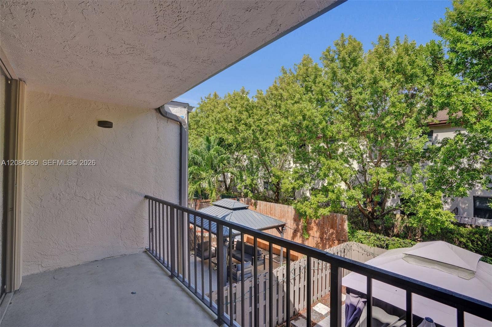Covered balcony featuring a concrete floor, stucco wall finish, and metal railing