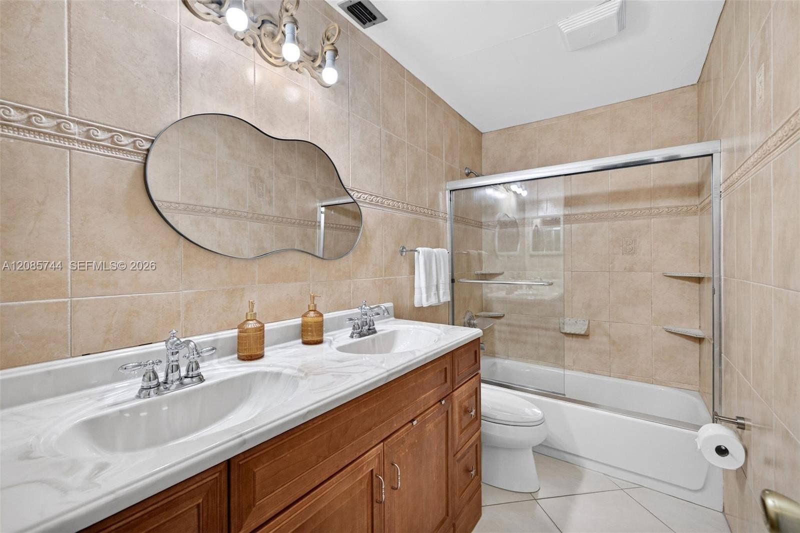 Guest bathroom w/ tub shower combo and dual vanity. Tile to the ceiling and glass enclosure