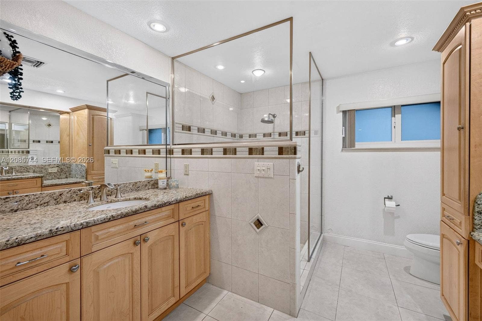 Ensuite bathroom w/ dual vanities w/ vanity area, stall shower & wood cabinets