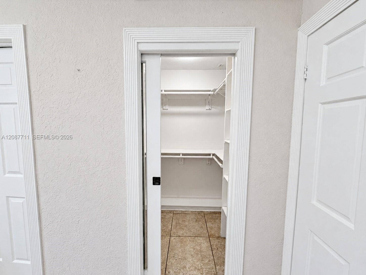 80 NE 162nd Street, Miami, Miami, FL 33162 Walk-in closet featuring a sliding door, tiered white shelving, and tiled flooring