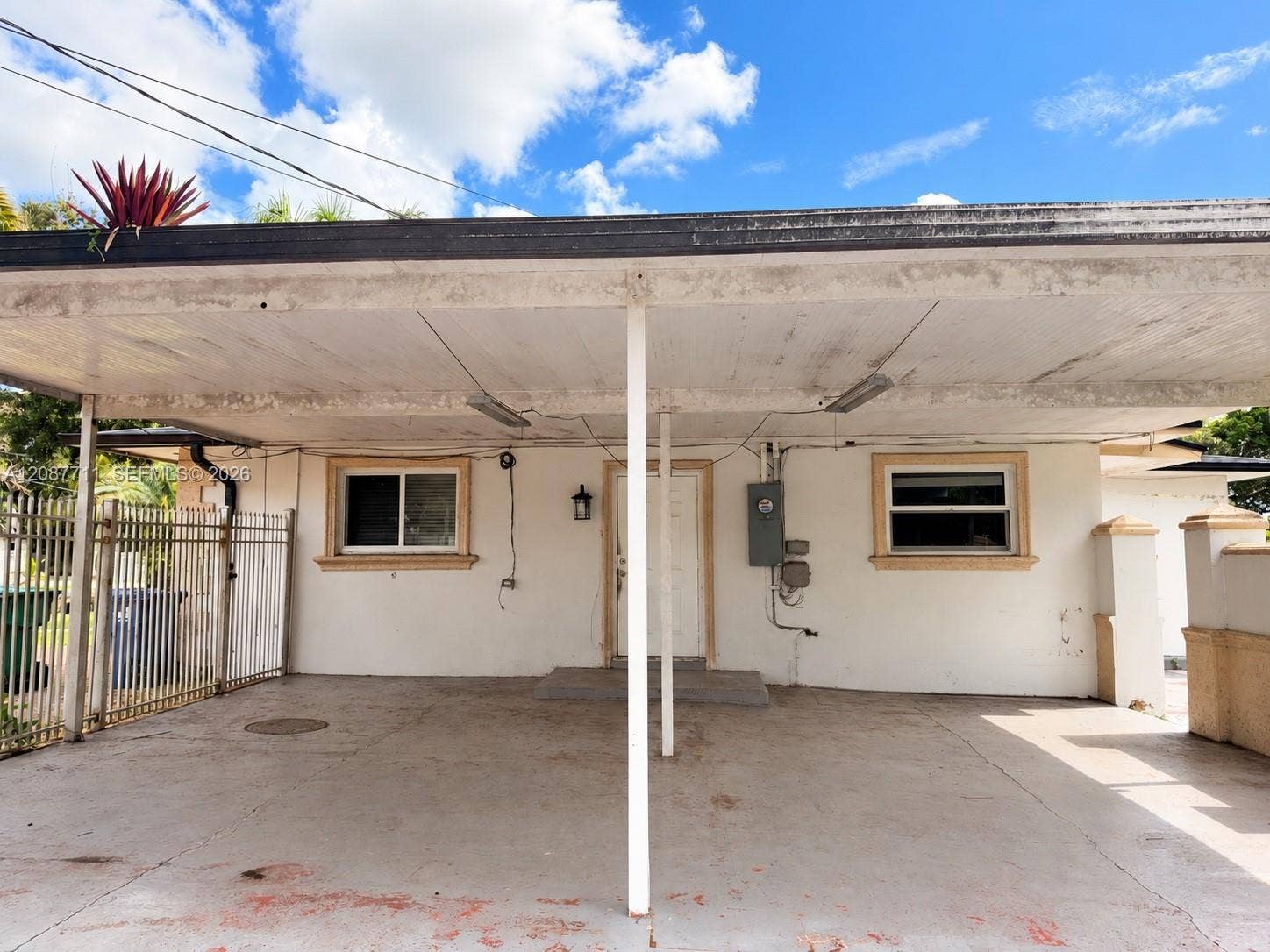 80 NE 162nd Street, Miami, Miami, FL 33162 Covered carport featuring a concrete floor, metal support columns, integrated lighting fixtures, and decorative masonry pillars
