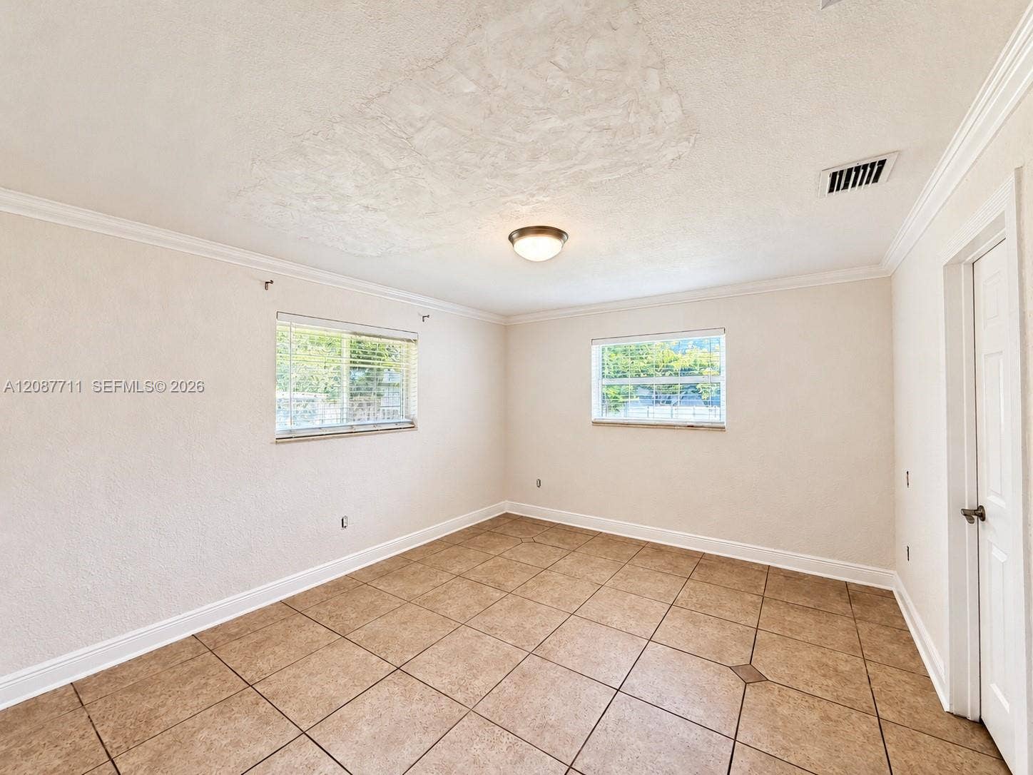 80 NE 162nd Street, Miami, Miami, FL 33162 Neutral interior featuring tile flooring, crown molding, and two windows with horizontal blinds