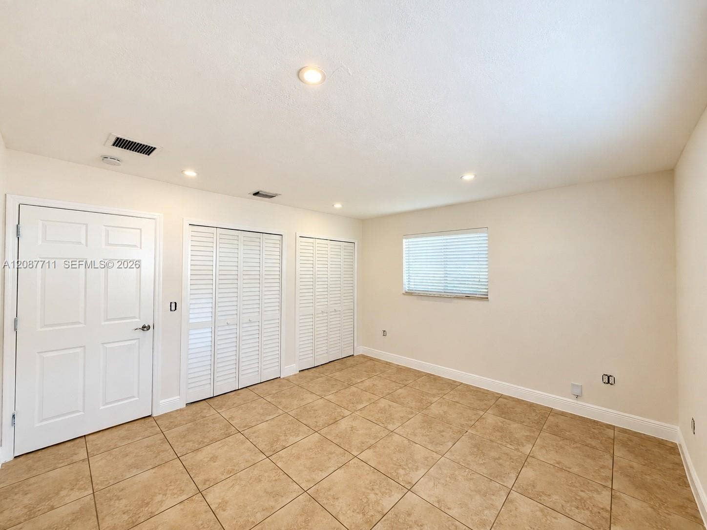 80 NE 162nd Street, Miami, Miami, FL 33162 Room featuring neutral tile flooring, recessed ceiling lighting, two sets of white louvered-style closet doors, and a single window with integrated blinds