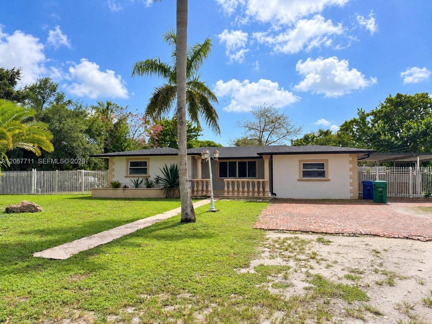 80 NE 162nd Street, Miami, Miami, FL 33162 Single-story exterior featuring a brick-paved driveway, decorative balustrade porch railing, quoin corner detailing, and a multi-paneled metal roof