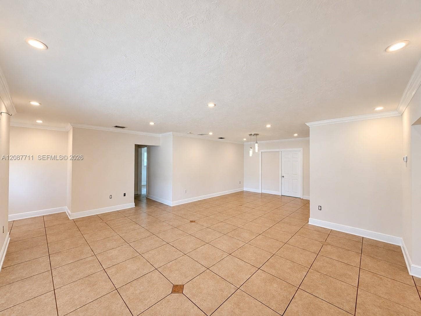 80 NE 162nd Street, Miami, Miami, FL 33162 Open-concept room featuring large-format ceramic tile flooring with decorative inserts, recessed lighting, crown molding, and a multi-pendant light fixture