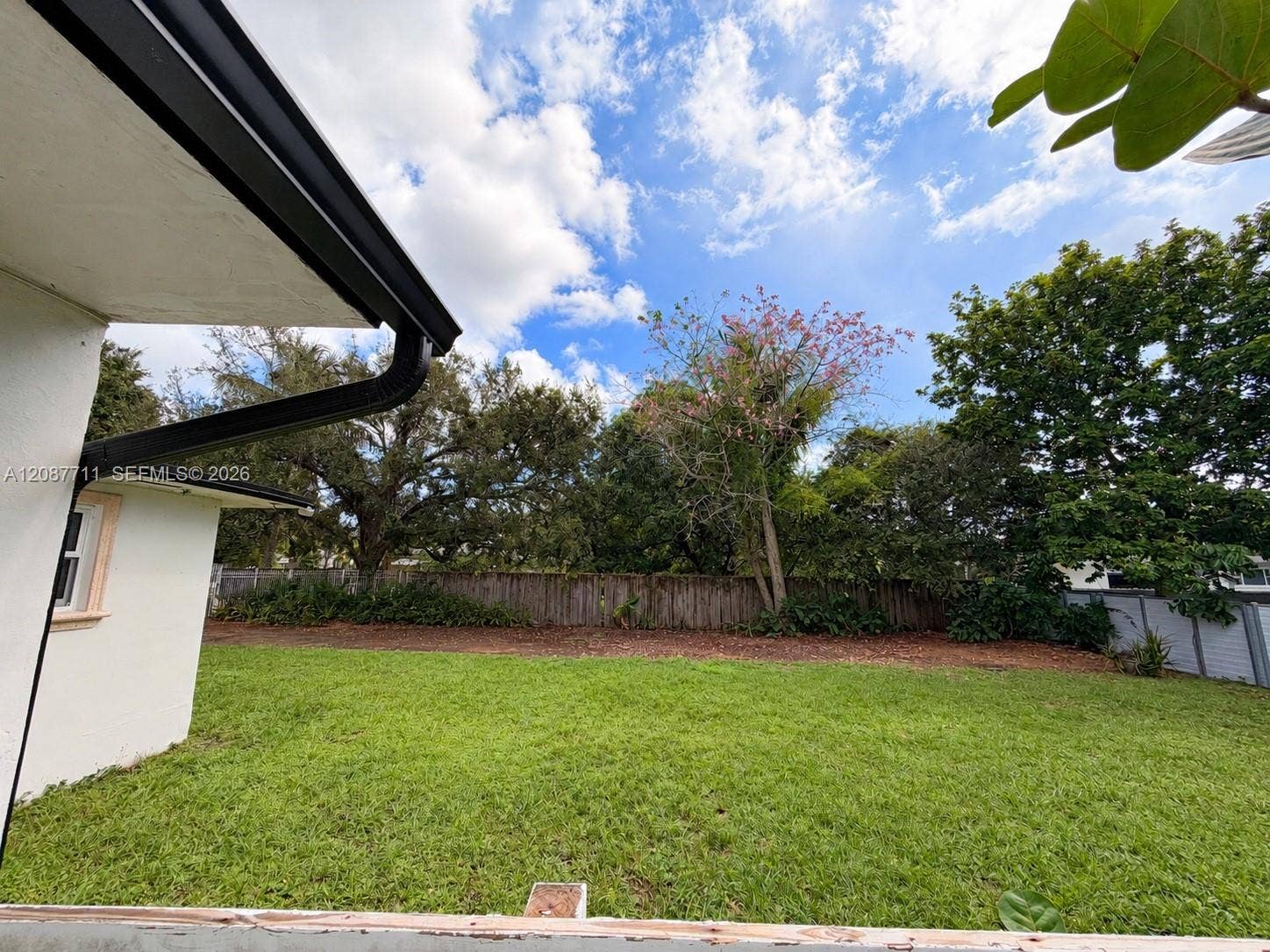 80 NE 162nd Street, Miami, Miami, FL 33162 Backyard featuring an expansive lawn, mature tree canopy, and wood fencing