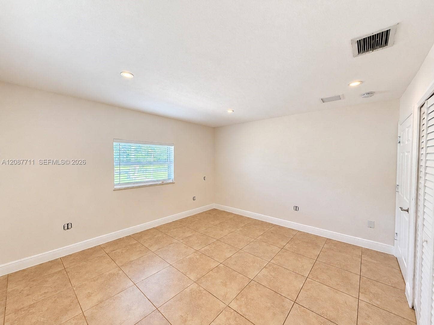80 NE 162nd Street, Miami, Miami, FL 33162 Interior space featuring neutral-toned tile flooring, recessed ceiling lighting, a single window, and a louvered bi-fold closet door