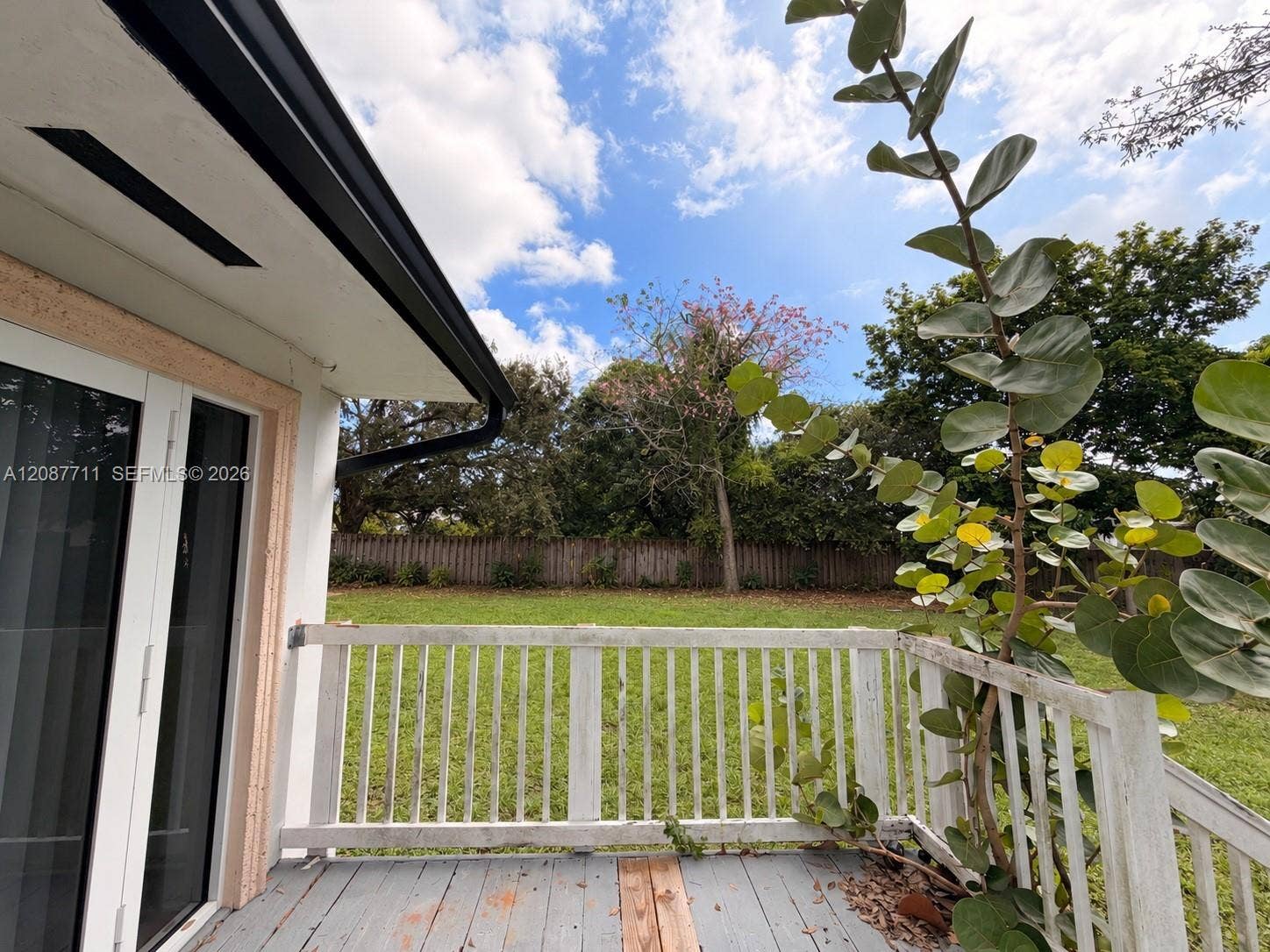 80 NE 162nd Street, Miami, Miami, FL 33162 Outdoor deck featuring white wooden railings, grey plank flooring, and dual glass-paneled exterior doors