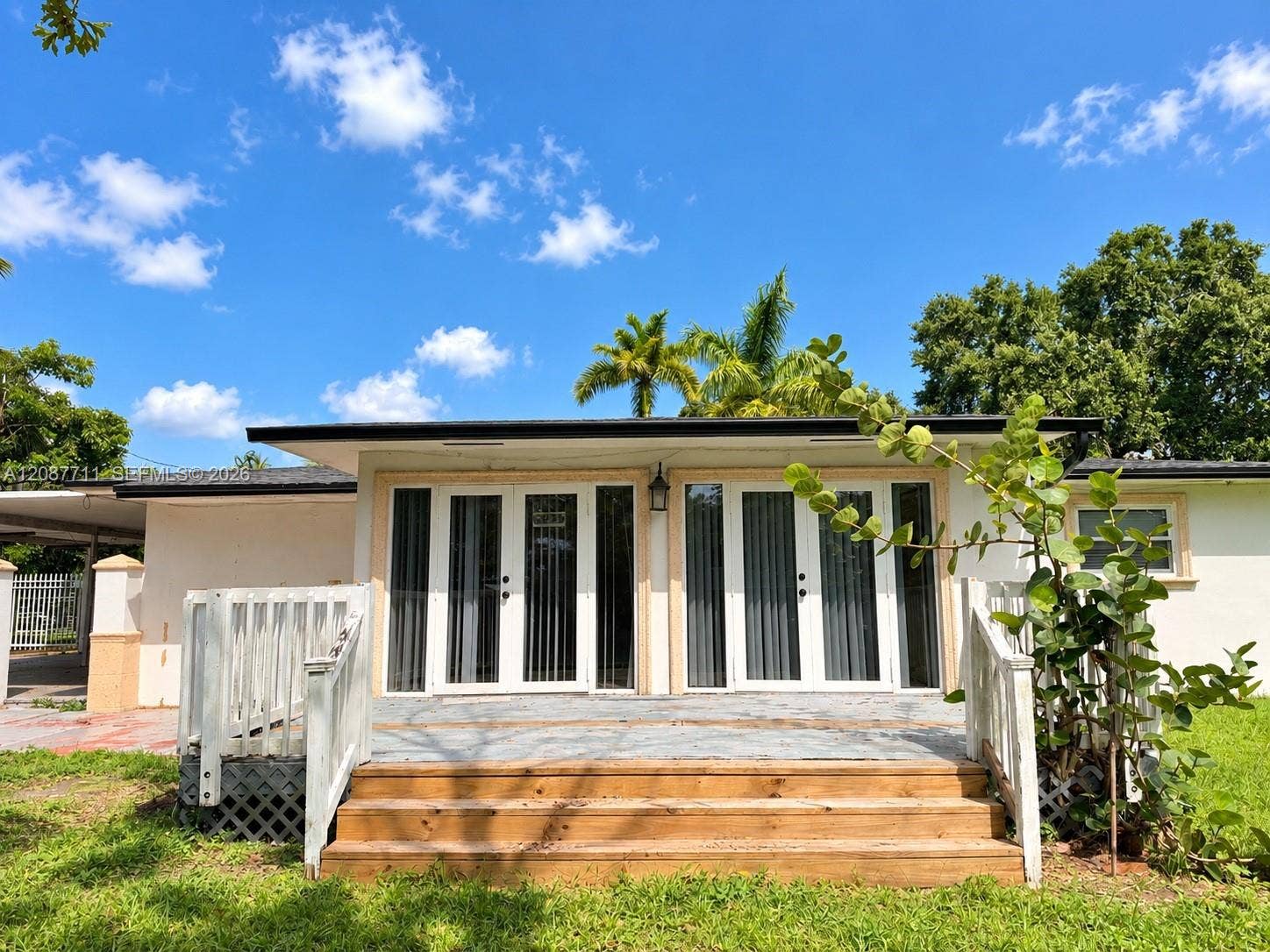 80 NE 162nd Street, Miami, Miami, FL 33162 Exterior deck featuring wood stairs, white railing, dual sets of glass-paned doors, and a covered patio area