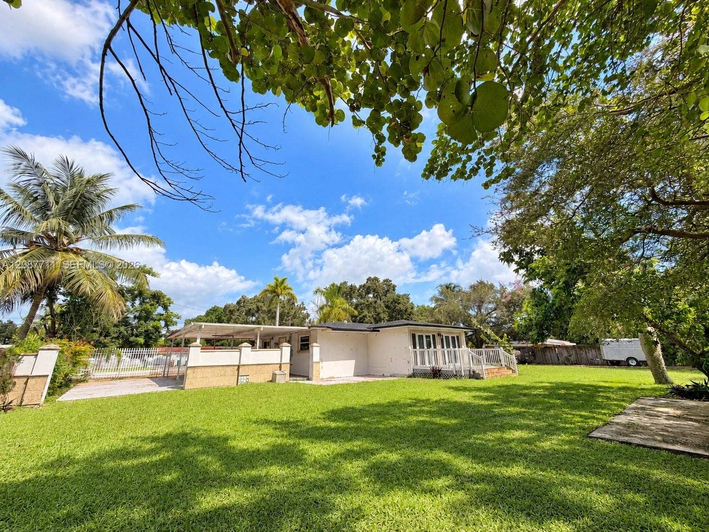 80 NE 162nd Street, Miami, Miami, FL 33162 Expansive lawn featuring mature trees, a covered patio, and perimeter masonry wall