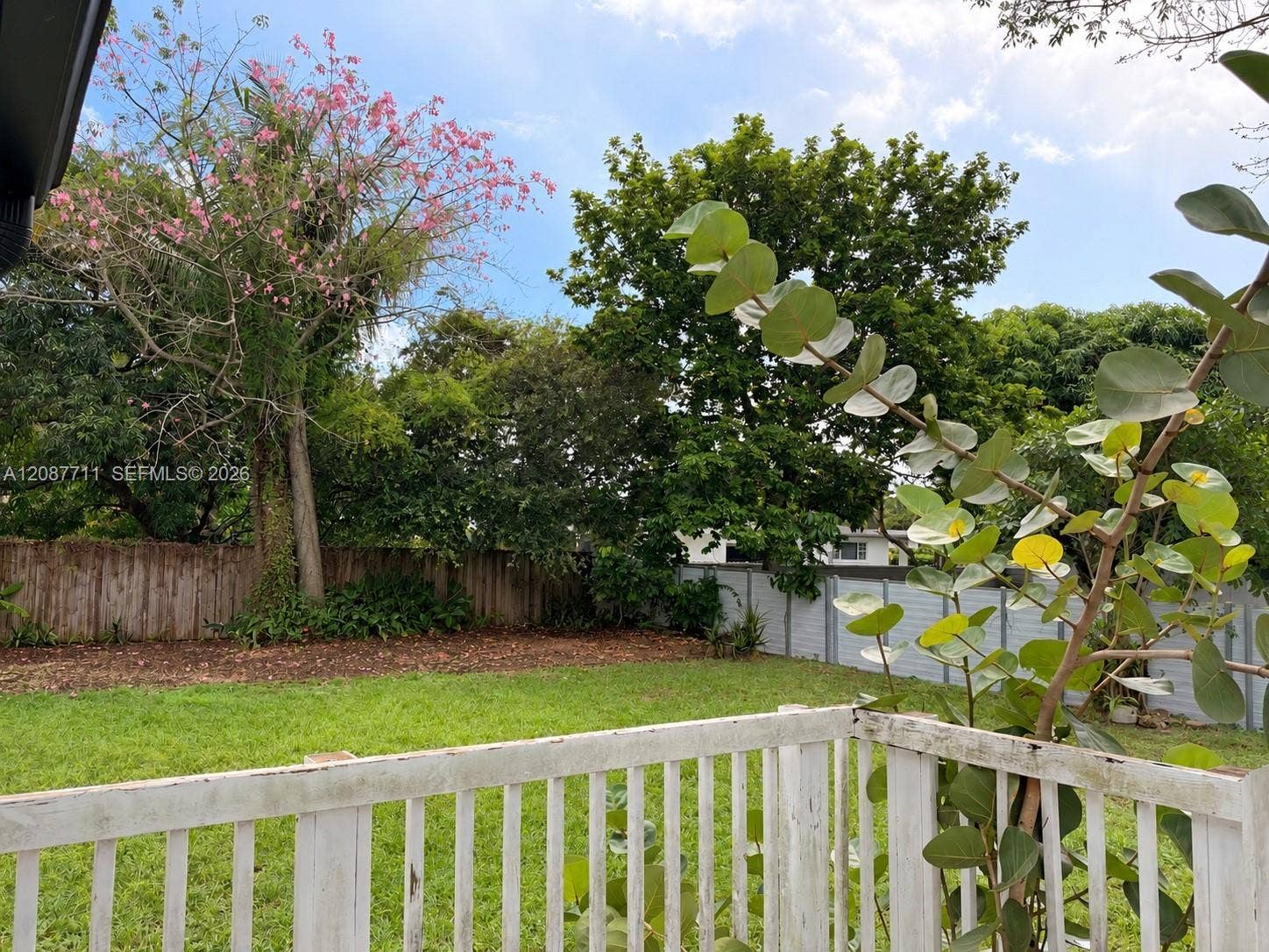 80 NE 162nd Street, Miami, Miami, FL 33162 Rear yard featuring a grass lawn, perimeter wood fencing, and mature trees