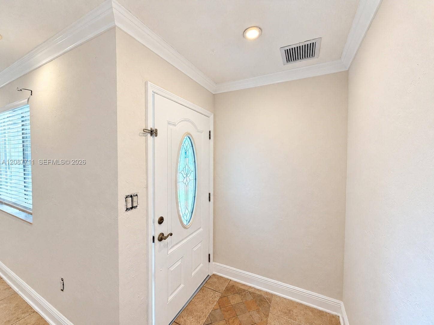 80 NE 162nd Street, Miami, Miami, FL 33162 Entryway featuring a white door with an oval glass insert, recessed lighting, crown molding, and stone tile flooring
