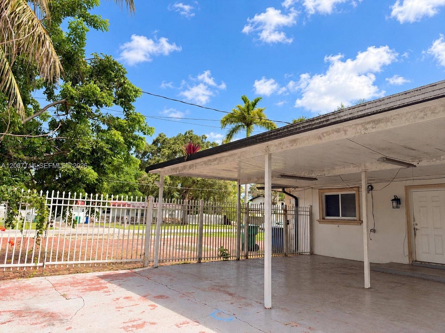 80 NE 162nd Street, Miami, Miami, FL 33162 Covered carport with concrete flooring, exterior wall-mounted light fixture, and perimeter metal fencing